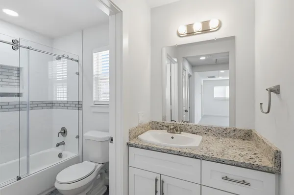 a bathroom with a granite countertop sink toilet and shower