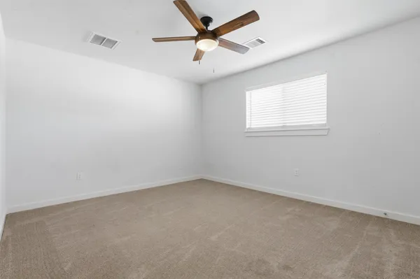 an empty room with a window and a fan