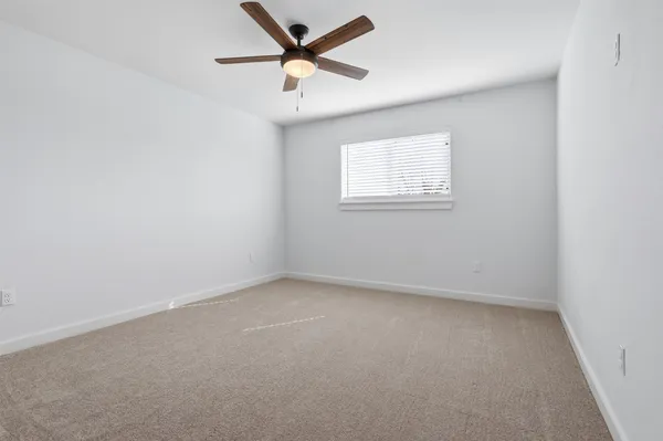 an empty room with a window and a fan