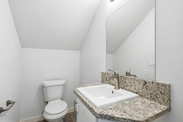 a bathroom with a granite countertop sink a toilet and mirror