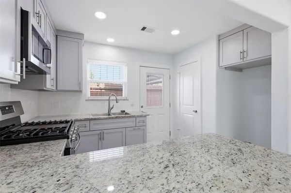 a kitchen with stainless steel appliances granite countertop a stove a sink and a refrigerator