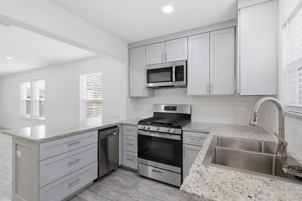a kitchen with granite countertop a stove a sink and a microwave