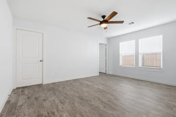 a view of empty room with wooden floor and fan