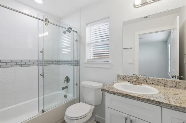 a bathroom with a granite countertop sink a toilet and shower