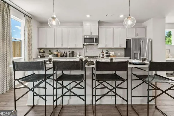 a kitchen with stainless steel appliances a dining table chairs and a refrigerator