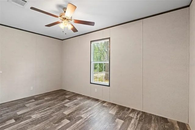 an empty room with a window and a ceiling fan