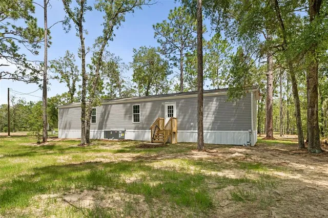 a view of a house with large yard and large tree
