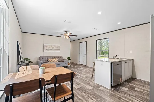 a kitchen with stainless steel appliances granite countertop a stove top oven a sink dishwasher and white cabinets with wooden floor