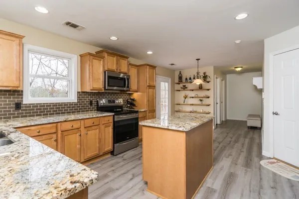 a kitchen with stainless steel appliances kitchen island granite countertop a stove and a sink