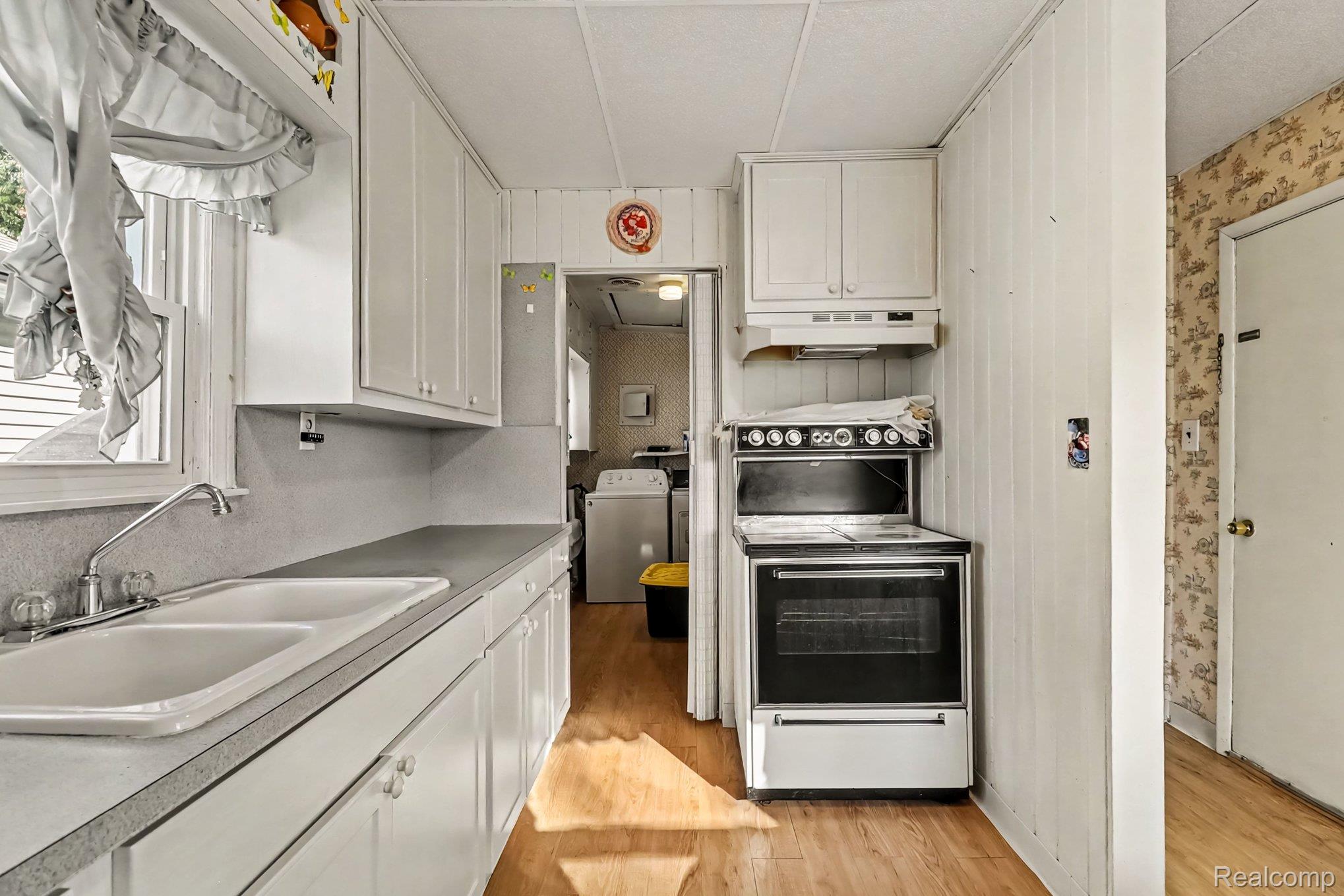 32694 Ruehle Avenue Warren, MI 48093 - Photo 6 of 15 White cabinetry, double basin sink, window, wood-finish flooring, and a white range