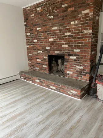 a view of empty room with wooden floor and fireplace