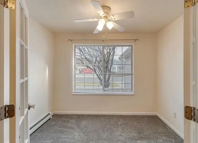 an empty room with a window and a fan