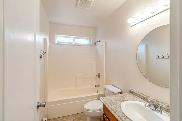 a bathroom with a granite countertop toilet a sink and a mirror
