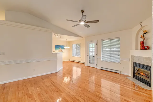 a view of an empty room with window and wooden floor
