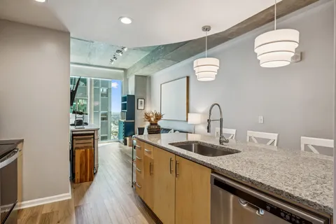 a kitchen with stainless steel appliances granite countertop a sink dishwasher and a stove with wooden floor