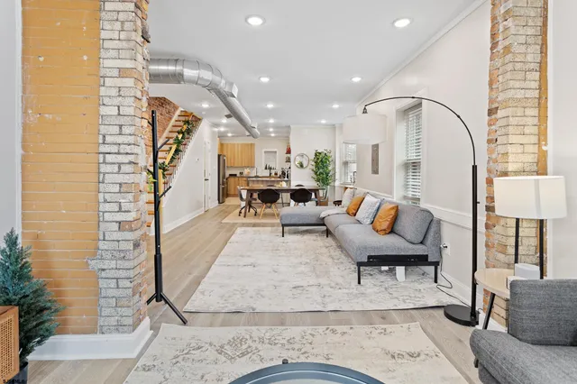 a living room with couches and kitchen view with wooden floor