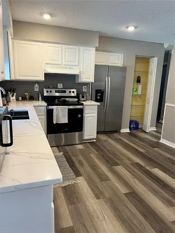 a kitchen with granite countertop a refrigerator stove and sink