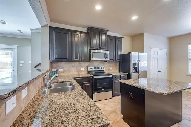 a kitchen with stainless steel appliances granite countertop a stove refrigerator sink and cabinets