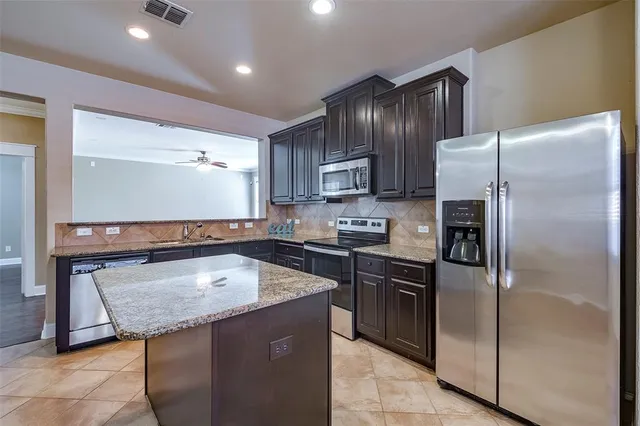 a kitchen with granite countertop a refrigerator and a stove top oven