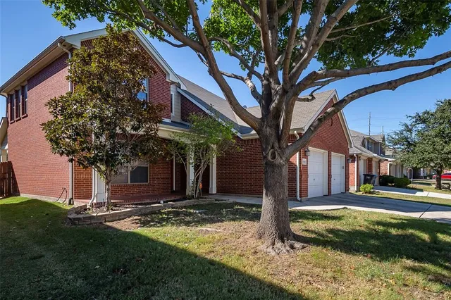 a tree in front of a house with a yard