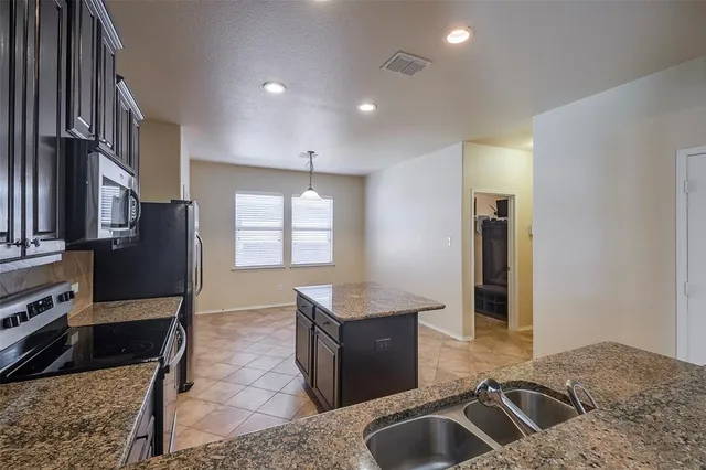a kitchen with stainless steel appliances granite countertop a sink a stove and a refrigerator
