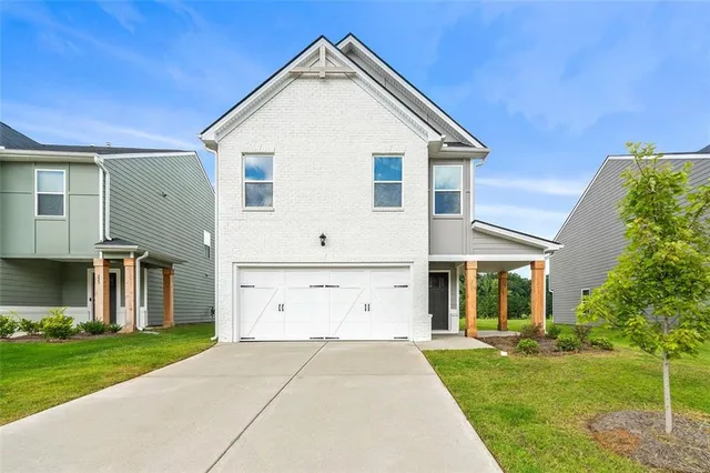 a view of a white house with a big yard and potted plants