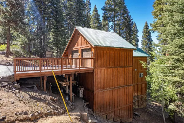 a view of a small house with wooden deck and furniture