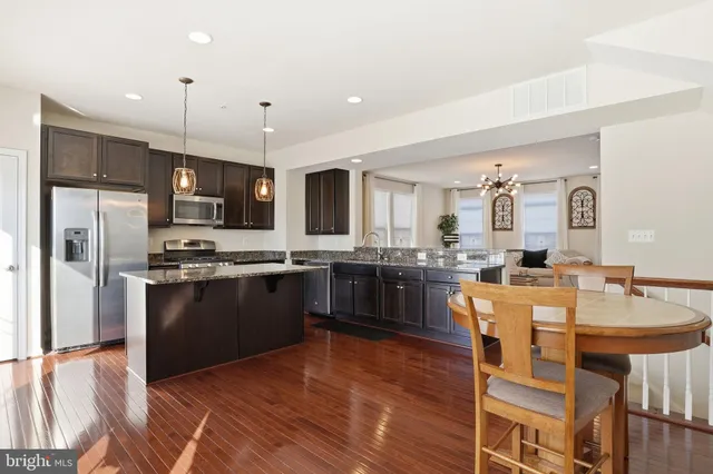 a kitchen with stainless steel appliances granite countertop a refrigerator a stove top oven a sink dishwasher and white cabinets with wooden floor