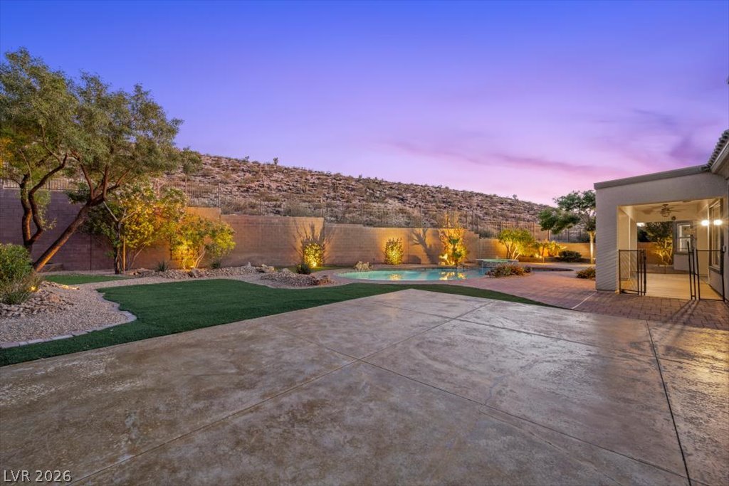 2125 De Rouge Avenue Henderson, NV 89044 - Photo 21 of 96 An inviting pool and patio oasis with desert landscaping, perfect for twilight relaxation.
