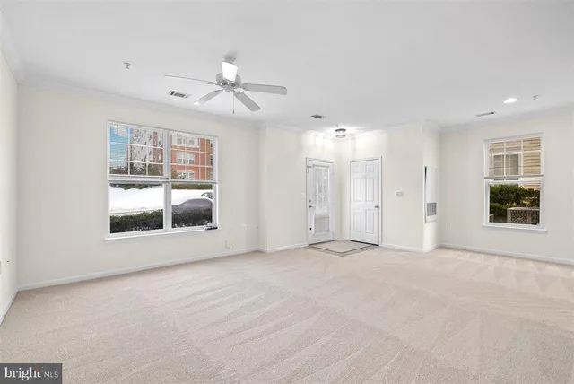an empty room with chandelier fan and windows