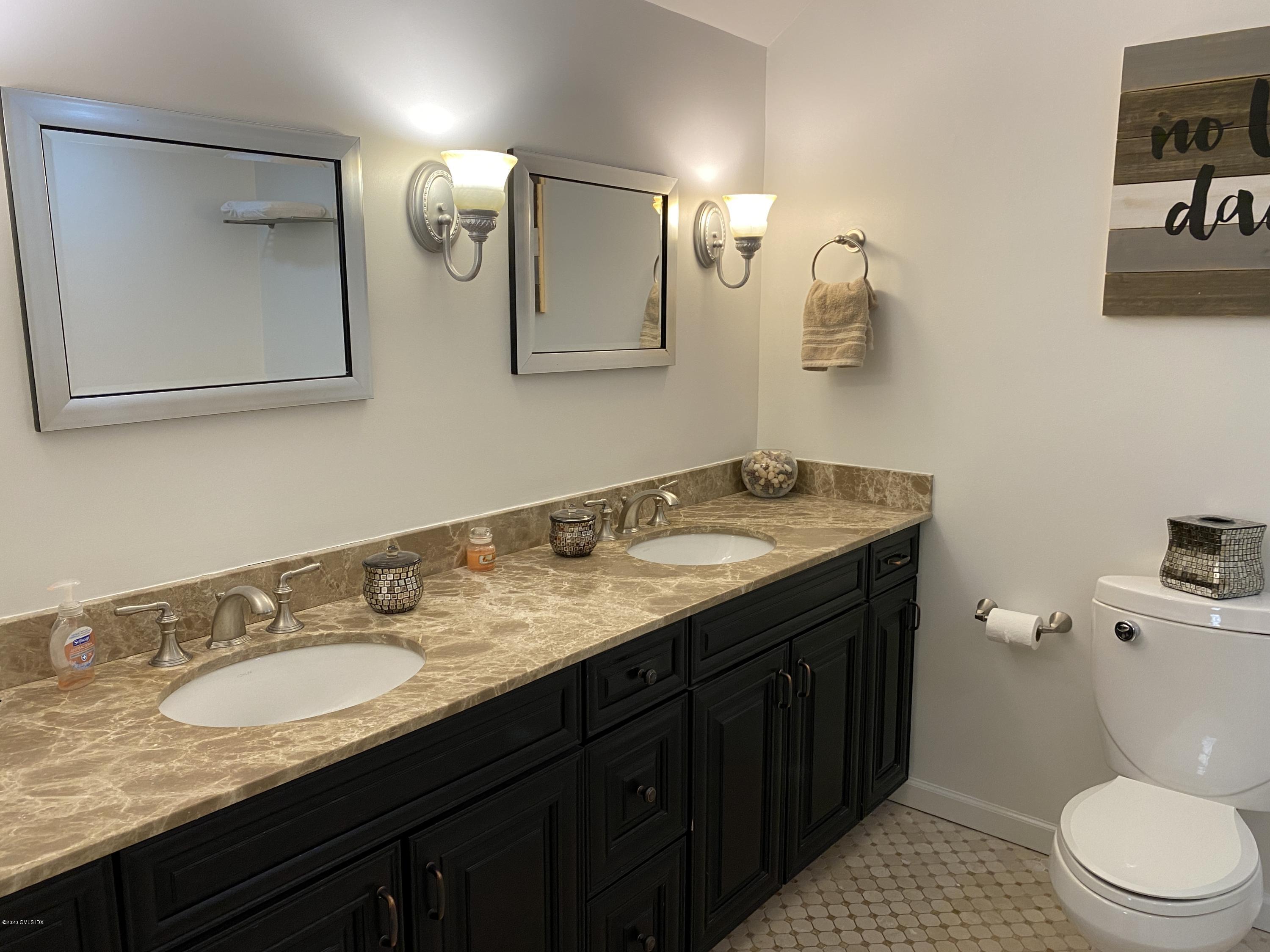 351 Pemberwick Road, Unit 607 Greenwich, CT 06831 - Photo 10 of 21 a bathroom with a granite countertop toilet sink and mirror