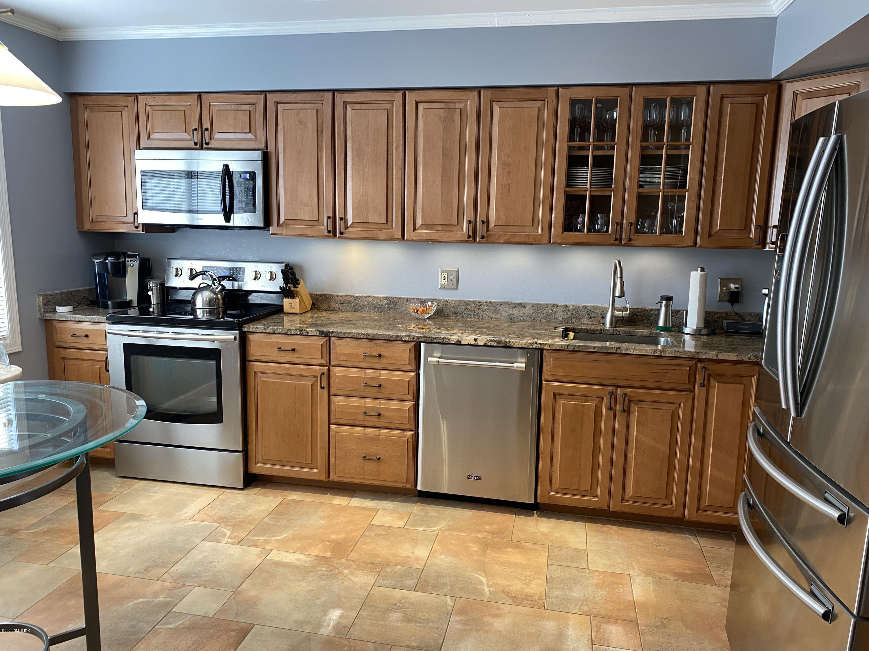 351 Pemberwick Road, Unit 607 Greenwich, CT 06831 - Photo 6 of 21 a kitchen with granite countertop a stove top oven microwave and cabinets