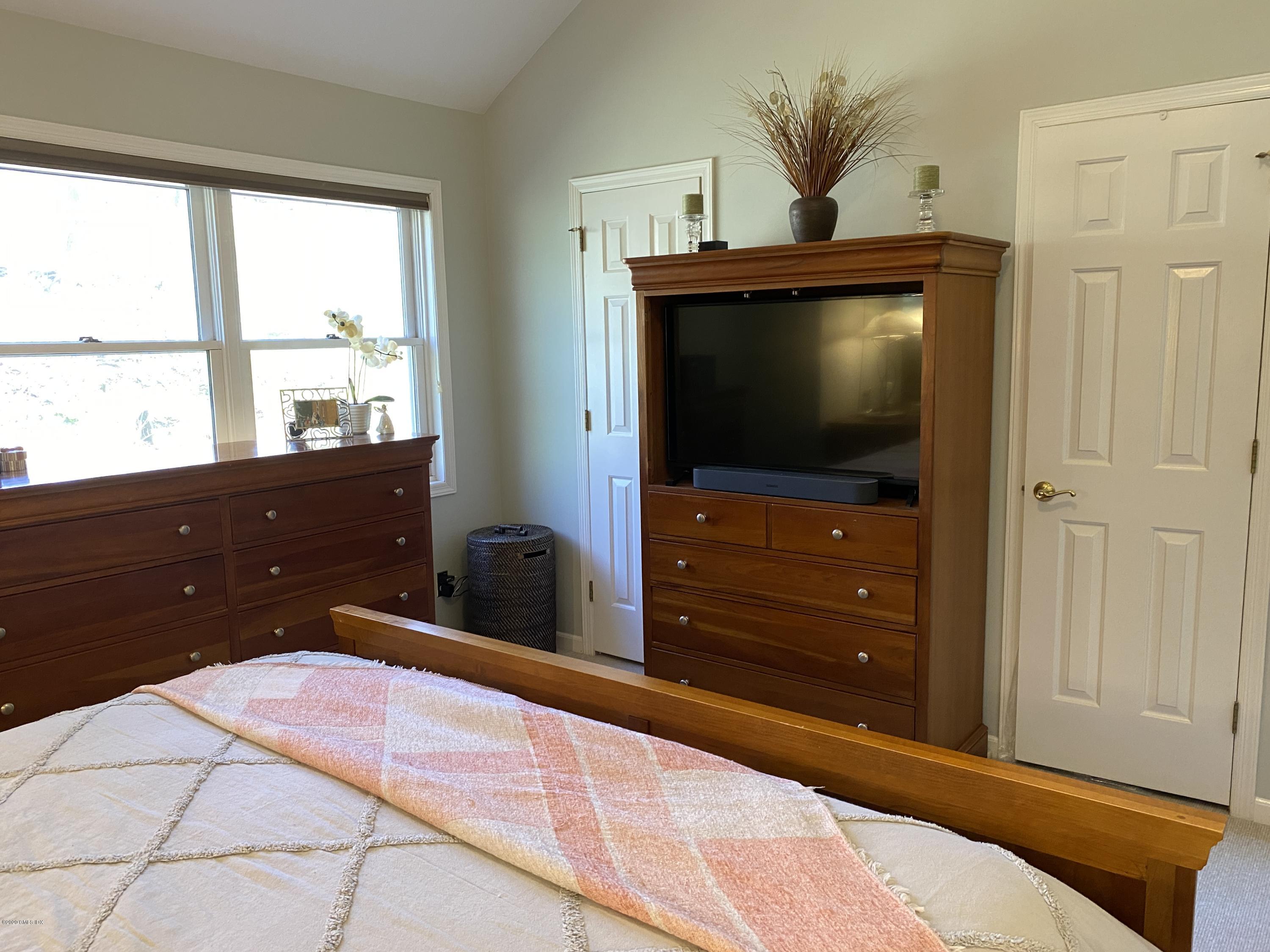 351 Pemberwick Road, Unit 607 Greenwich, CT 06831 - Photo 9 of 21 a bedroom with a bed and a flat tv screen on dresser