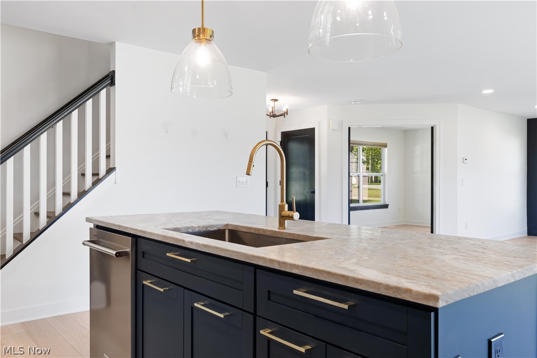 35799 Lorain Road North Ridgeville, OH 44039 - Photo 16 of 50 Kitchen featuring a center island with sink, sink, hanging light fixtures, light wood-type flooring, and light stone countertops