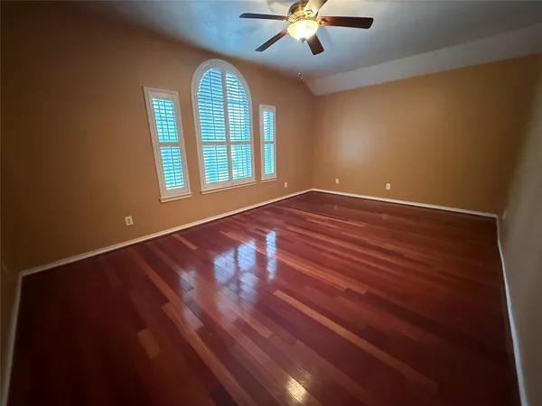 an empty room with wooden floor chandelier and windows