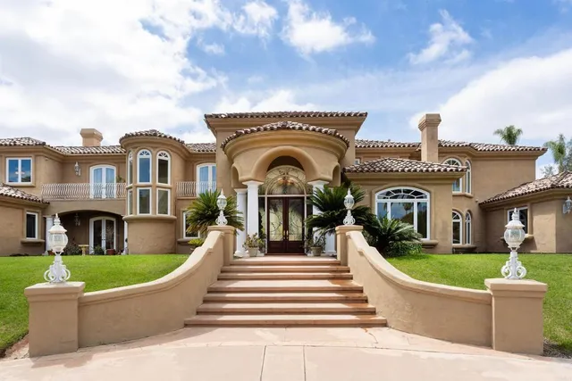 a view of a brick house with a large windows and a big yard with plants