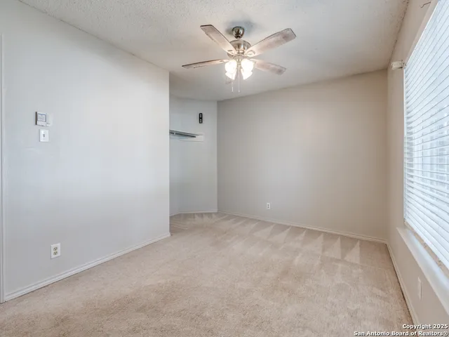 an empty room with a chandelier fan and windows