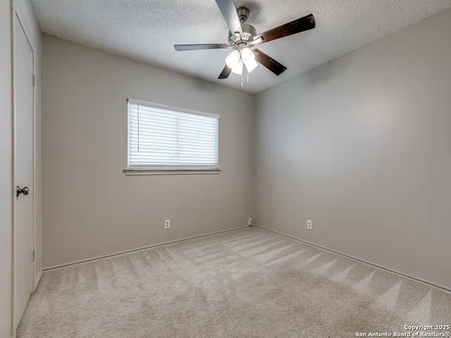 an empty room with a window and a fan