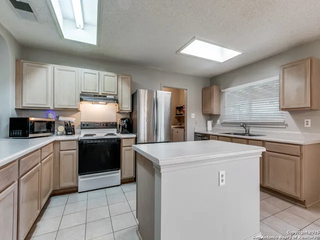 a kitchen with stainless steel appliances granite countertop a refrigerator sink stove microwave and cabinets