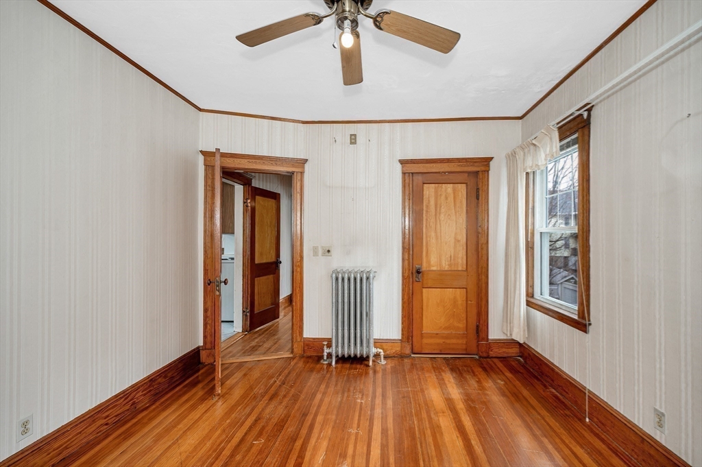481 Lagrange Street Boston, MA 02132 - Photo 9 of 32 an empty room with wooden floor chandelier fan and windows