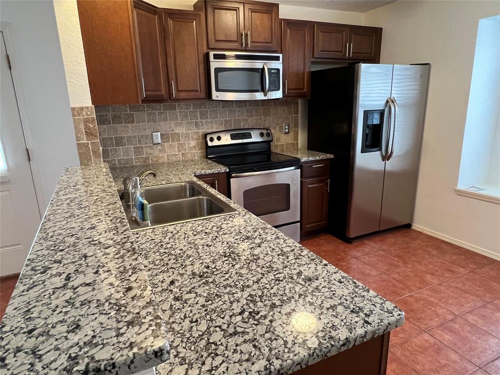 a kitchen with stainless steel appliances granite countertop a refrigerator a stove a sink and a microwave