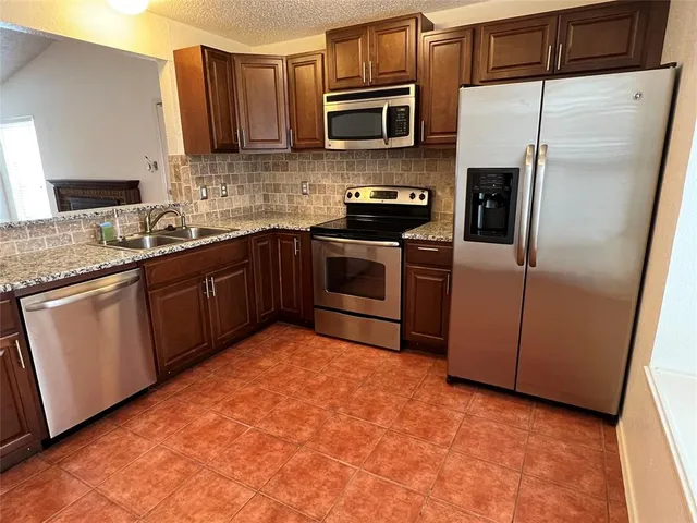 a kitchen with stainless steel appliances granite countertop a stove a sink and a refrigerator