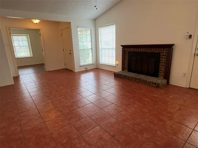 an empty room with windows and fireplace