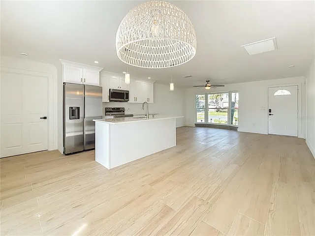 a view of a kitchen with a sink dishwasher and a large mirror with wooden floor