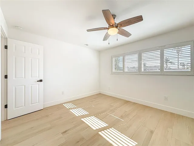 a view of an empty room with a ceiling fan and a window
