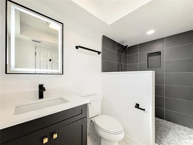 a bathroom with a sink a toilet a mirror and shower