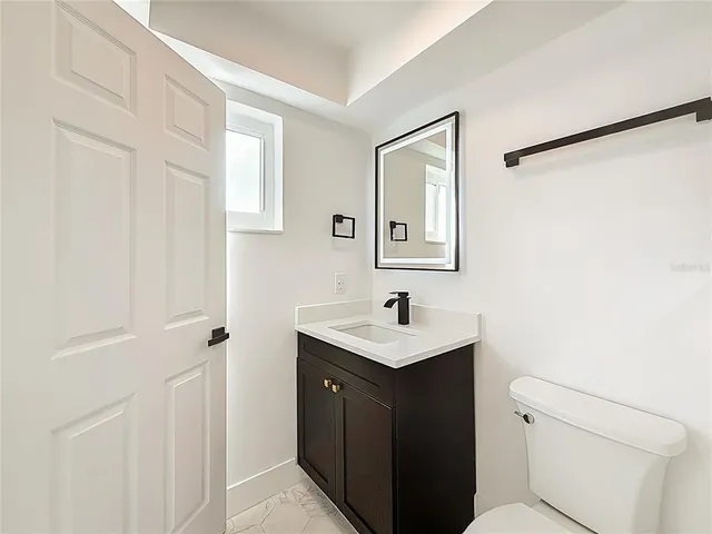 a bathroom with a toilet a sink a mirror and vanity