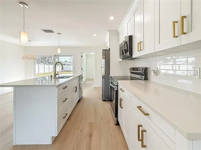 a large kitchen with stainless steel appliances sink a microwave and cabinets