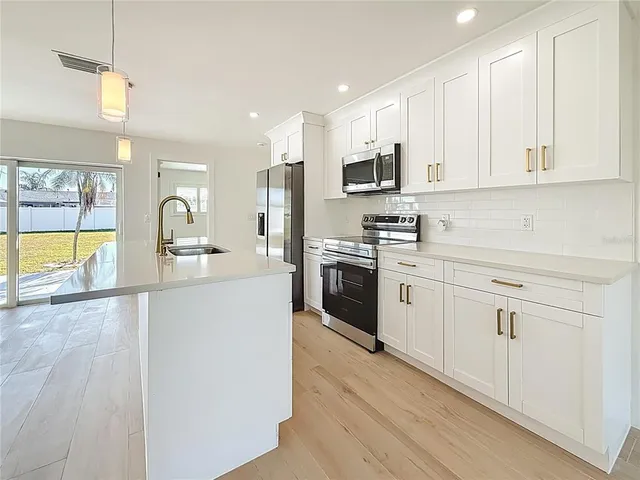 a kitchen with stainless steel appliances granite countertop white cabinets a sink a stove a refrigerator and white cabinets