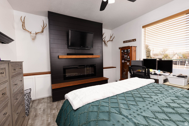 197 West 100 South Redmond, UT 84652 - Photo 16 of 41 Bedroom featuring a fireplace, light wood-type flooring, a ceiling fan, and a desk